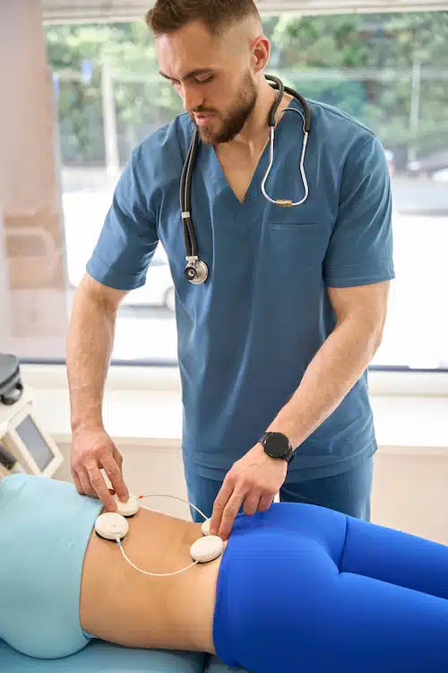 physical therapist performing ems seesion Electrical Muscle Stimulation to patients back