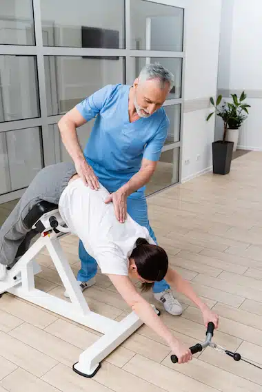 physical therapist supporting woman in rehabilitation therapeutic exercises