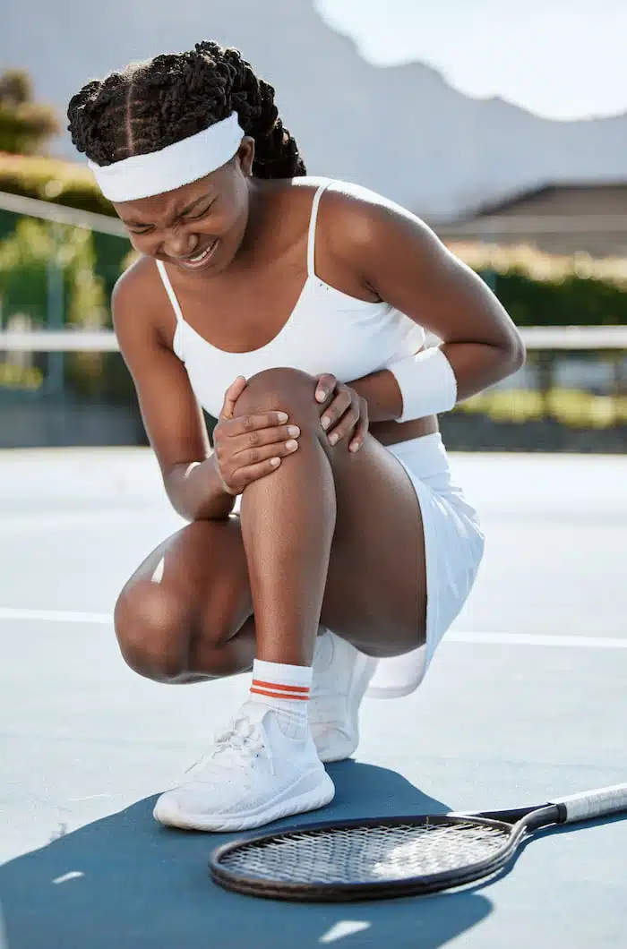 woman tennis athlete experiencing sports injuries needing massage therapy