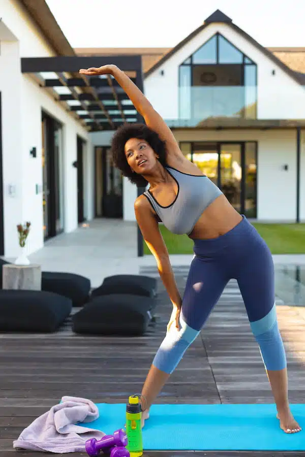 Young african american afro woman doing stretching exercise in backyard experiencing pain relief after spinal decompression therapy