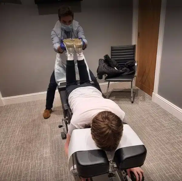 A medical professional performing an assessment or adjustment on a patient lying on a treatment table as part of a personal injury treatment