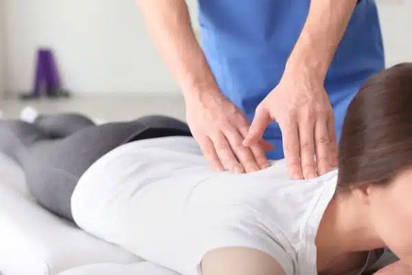 Practitioner performing hands-on spinal treatment on a patient lying face-down.