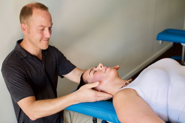 A physical chiropractor performing a neck adjustment on a female patient as part of a personal injury treatment plan