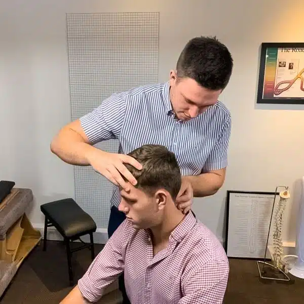 Chiropractor gently assessing and adjusting a patient’s cervical spine during treatment.